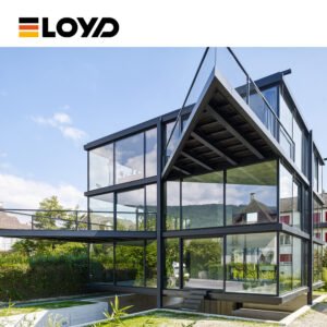 ELOYD modern multi-story building with black frames, slanted roof, and extensive glass facades, nestled among greenery with mountain views.