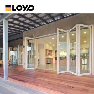White ELOYD folding glass doors fully open from a wooden deck into a bright modern kitchen and living area.