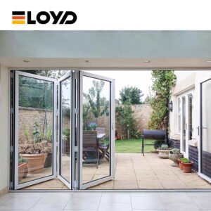 ELOYD white folding patio doors fully opened to a landscaped garden with greenery, outdoor furniture, and a barbecue grill.
