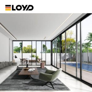 Modern minimalist living room by ELOYD featuring a light gray sofa, green armchair, wood coffee table, and large black-framed glass doors opening to a view of a pool and greenery.