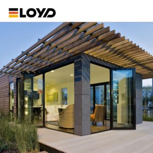 A modern sunroom by ELOYD with large black glass folding doors, a wooden deck, and a slatted pergola roof, featuring cozy indoor seating.